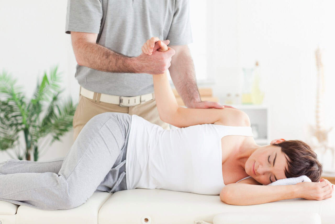 A physical therapist stretching a patient's shoulder