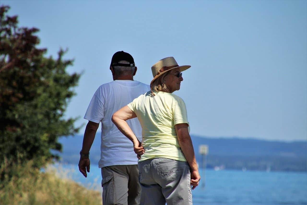 An older couple walking by the water