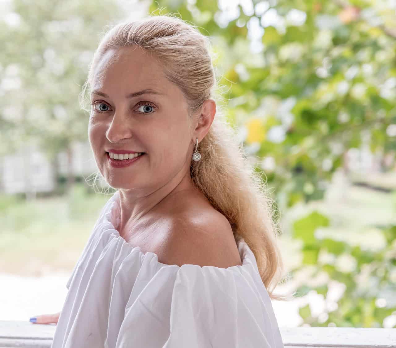 A smiling woman with blond hair outdoors